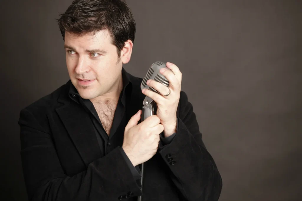 Josh Baty, top New Jersey singer known for his lifelike covers, posing with a vintage microphone