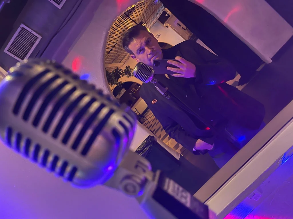 Josh Baty preparing to sing beside a vintage microphone at a live North Jersey performance