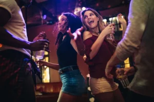 Friends dancing and enjoying drinks during a lively restaurant entertainment experience