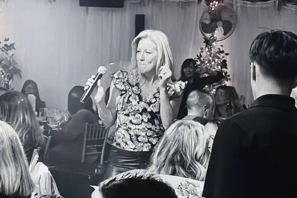 Female singer performing with a microphone among guests at a private party in New Jersey