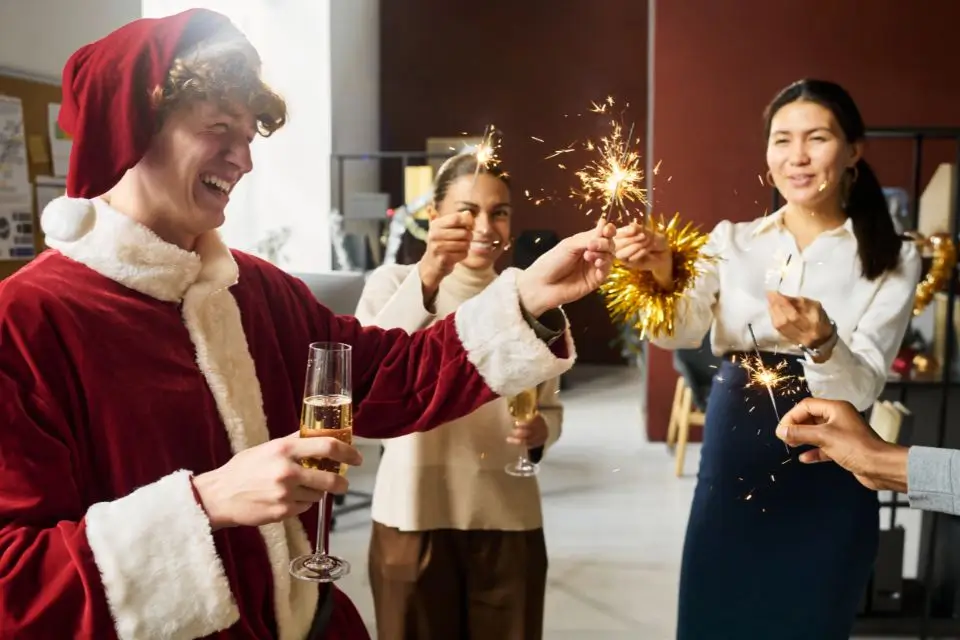 Coworkers celebrating an employee holiday party with sparklers and champagne