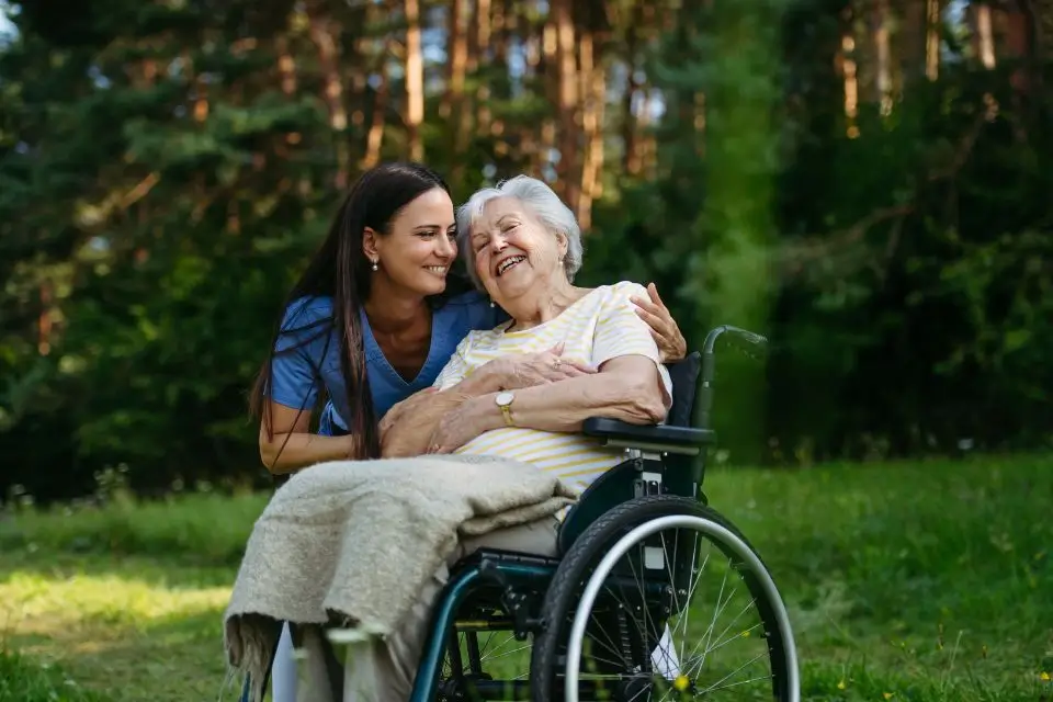 Caregiver spending time outdoors with an older woman at a senior care retirement community