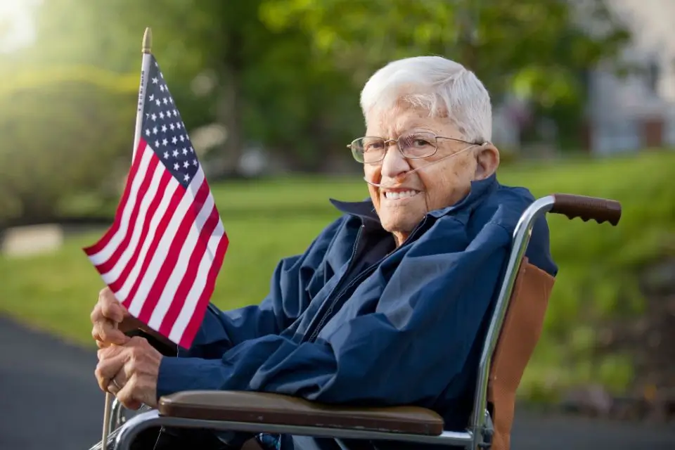 Older veteran holding an American flag at a senior living community party with live music