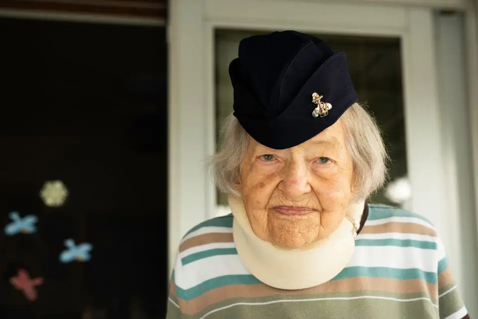 Elderly woman veteran wearing a military service cap at a senior residence